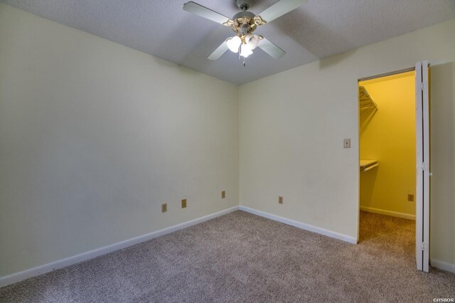 empty room with a ceiling fan, light carpet, a textured ceiling, and baseboards