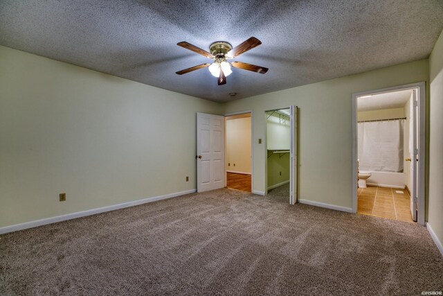 unfurnished bedroom featuring light carpet, a textured ceiling, ensuite bath, and baseboards