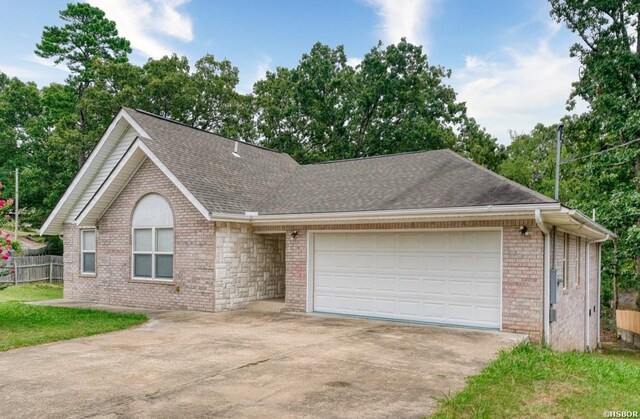 ranch-style house with an attached garage, brick siding, fence, concrete driveway, and roof with shingles