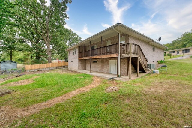 rear view of house featuring a deck, a patio, brick siding, fence, and a lawn