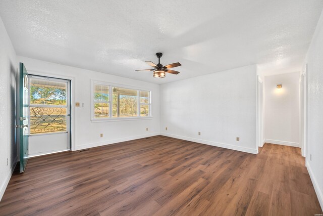 spare room featuring dark wood-style floors, ceiling fan, a textured ceiling, and baseboards