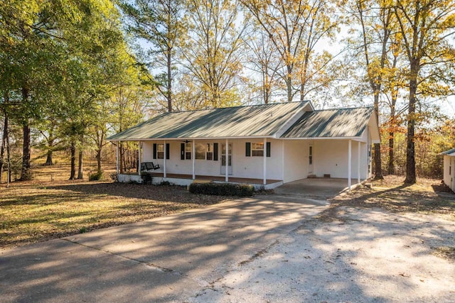 view of front of house with driveway, covered porch, metal roof, and a carport