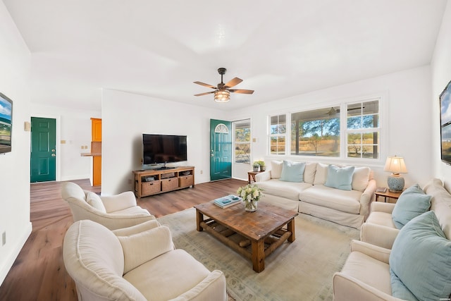 living area with ceiling fan, plenty of natural light, and light wood-style floors