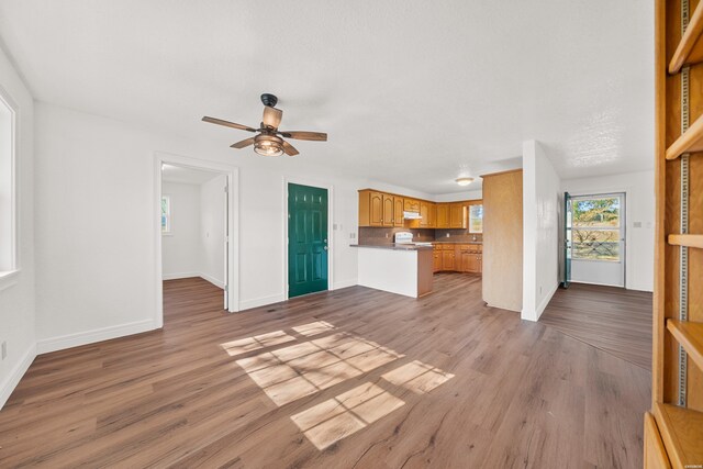 unfurnished living room featuring baseboards, a ceiling fan, and light wood-style floors