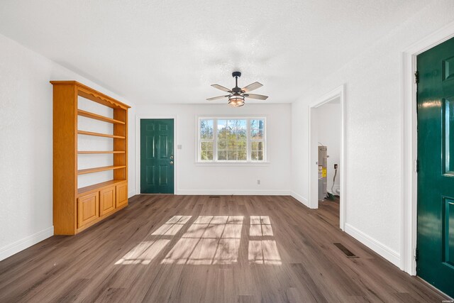 unfurnished living room featuring a ceiling fan, baseboards, visible vents, and dark wood-style flooring