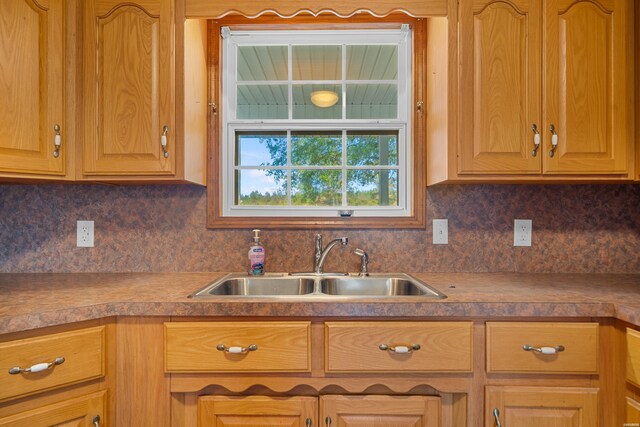 kitchen featuring brown cabinetry, a sink, and decorative backsplash