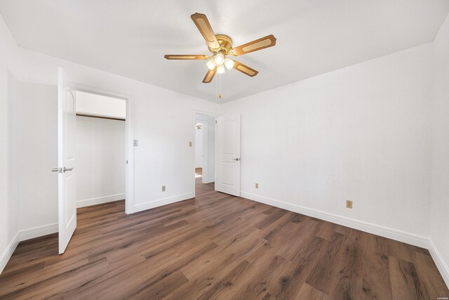 unfurnished bedroom with a closet, baseboards, dark wood finished floors, and a ceiling fan