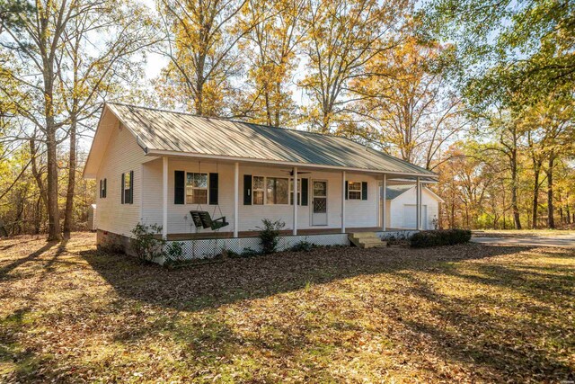 view of front facade featuring a porch, a front yard, metal roof, and a garage