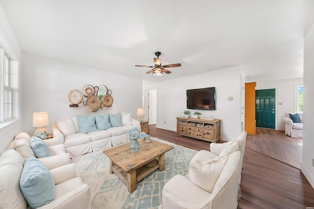 living area featuring ceiling fan, baseboards, and wood finished floors