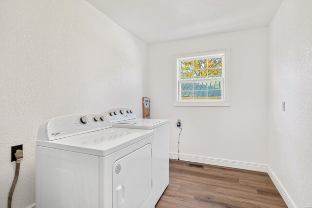 laundry area with light wood-style flooring, laundry area, separate washer and dryer, visible vents, and baseboards