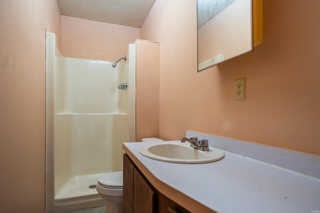 full bathroom with toilet, a textured ceiling, a shower stall, and vanity