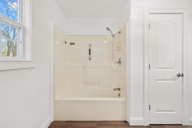 bathroom featuring  shower combination, wood finished floors, and baseboards