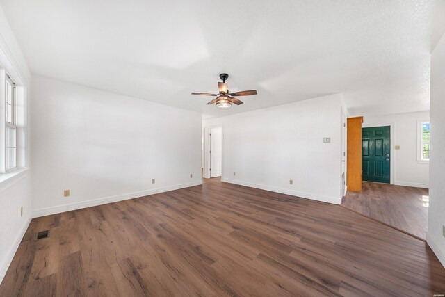 spare room featuring visible vents, dark wood finished floors, baseboards, and ceiling fan