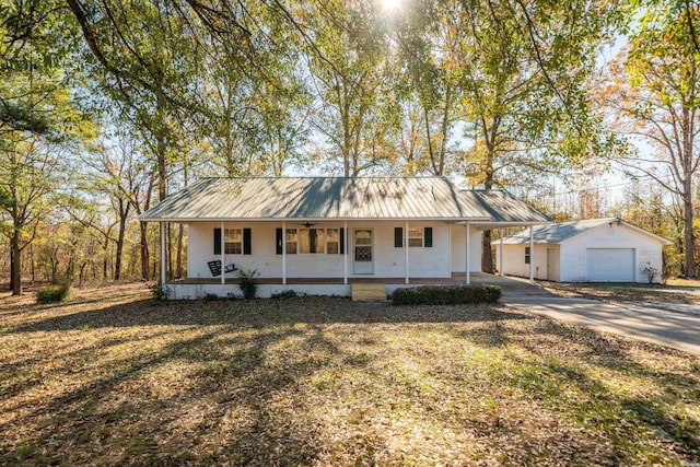 view of front of home featuring driveway, metal roof, an outdoor structure, a porch, and a front yard