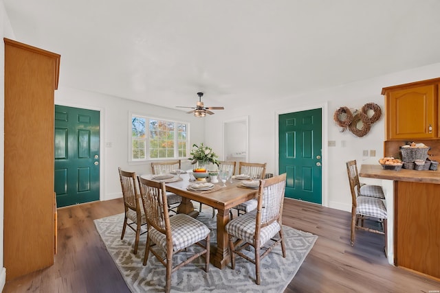 dining room featuring light wood-type flooring, a ceiling fan, and baseboards