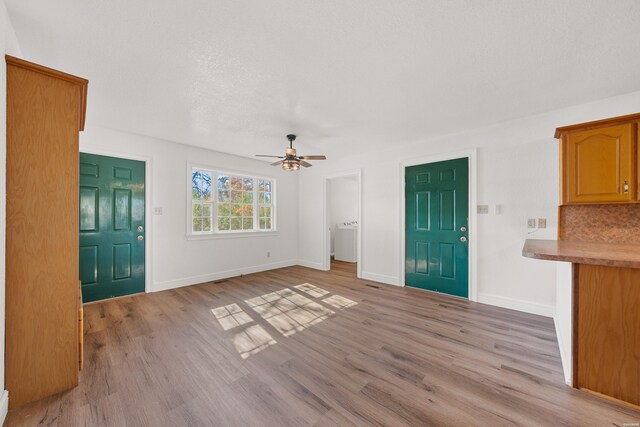 entrance foyer featuring light wood-type flooring, ceiling fan, baseboards, and washer / clothes dryer