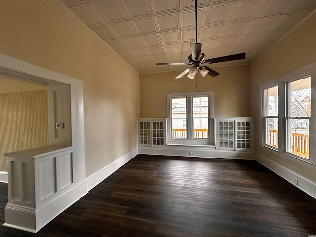 unfurnished room featuring a ceiling fan, an ornate ceiling, baseboards, and dark wood-style flooring