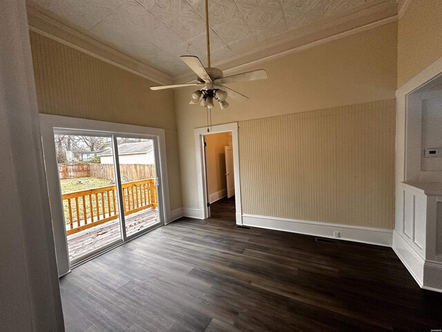 empty room with an ornate ceiling, dark wood finished floors, ornamental molding, a ceiling fan, and baseboards