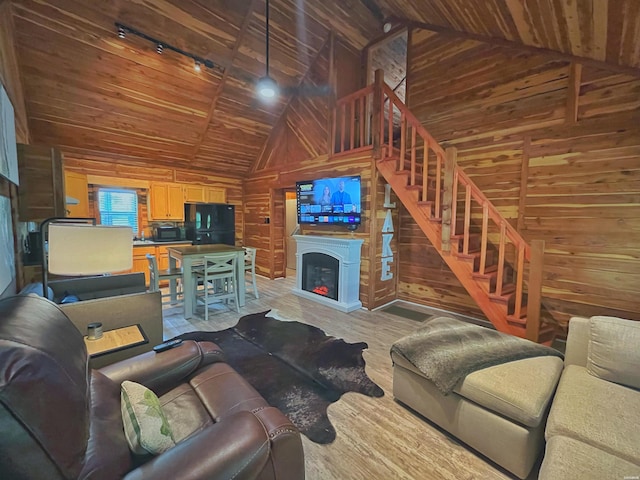 150 Shady Oak Trl, Hot Springs, AR 71913 - living room featuring wooden walls, light wood finished floors, rail lighting, stairs, and vaulted ceiling