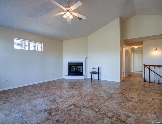 unfurnished living room with a fireplace with raised hearth, ceiling fan, visible vents, baseboards, and vaulted ceiling