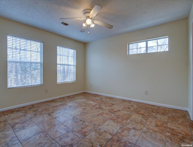 unfurnished room featuring a wealth of natural light, visible vents, ceiling fan, and a textured ceiling