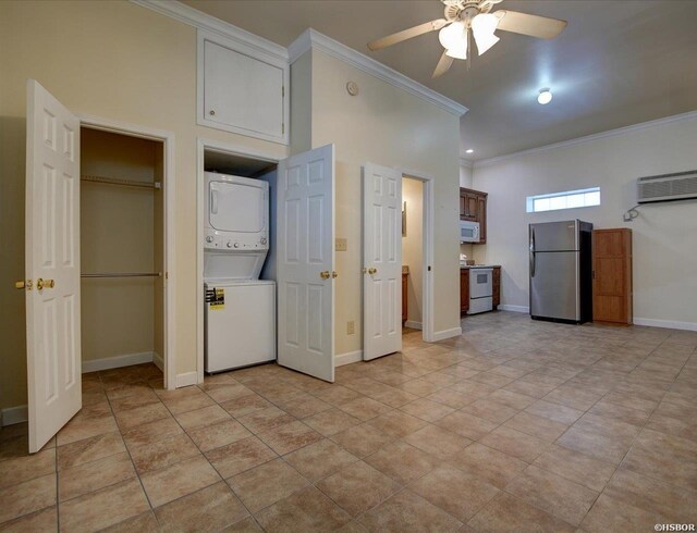 kitchen featuring white appliances, baseboards, a ceiling fan, stacked washer / dryer, and crown molding