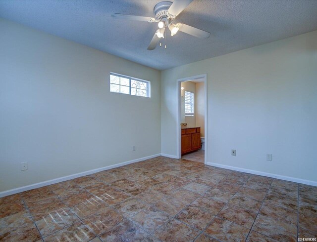 empty room featuring a textured ceiling, a ceiling fan, and baseboards