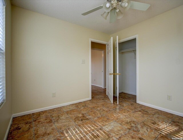 unfurnished bedroom featuring a ceiling fan, a closet, baseboards, and a textured ceiling