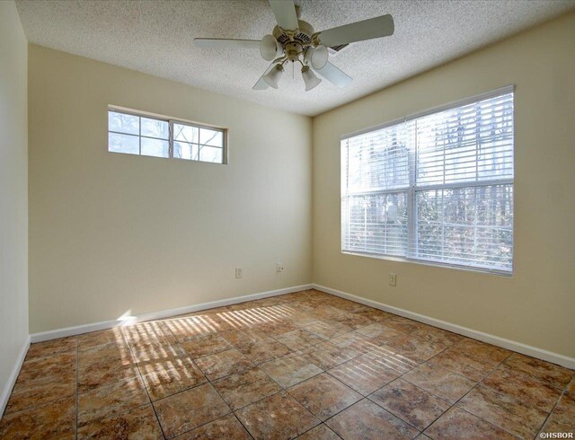 empty room with a textured ceiling, baseboards, and a healthy amount of sunlight