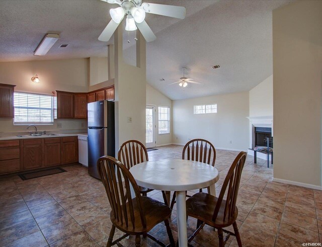 dining space with a healthy amount of sunlight, a fireplace, visible vents, and a textured ceiling