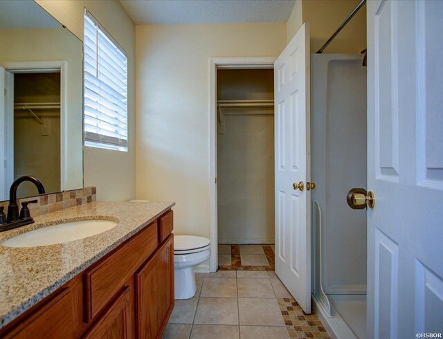 full bathroom with toilet, vanity, a spacious closet, a shower, and tile patterned floors