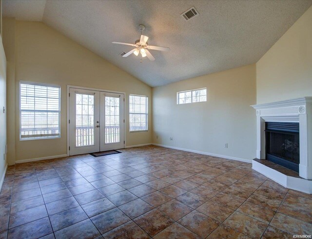 unfurnished living room with a fireplace with raised hearth, ceiling fan, a textured ceiling, visible vents, and french doors