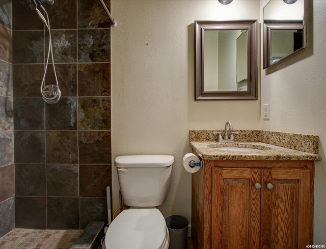 bathroom with a shower stall, vanity, and toilet