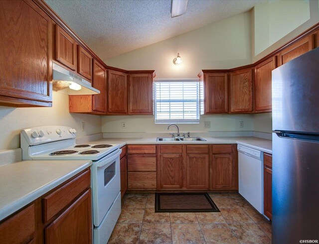 kitchen with under cabinet range hood, white appliances, a sink, light countertops, and brown cabinets