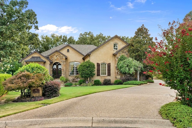 french country inspired facade featuring stone siding, a front lawn, and stucco siding