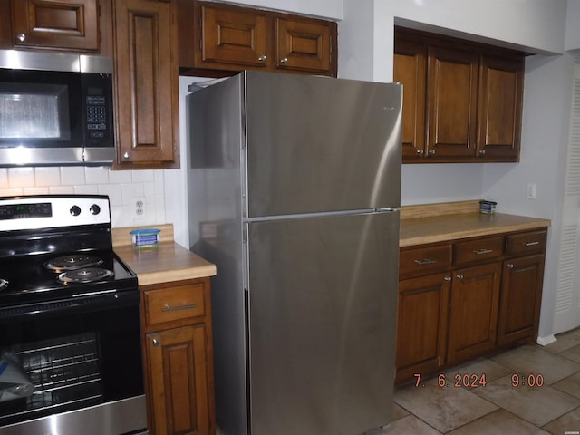 kitchen featuring light tile patterned floors, light countertops, appliances with stainless steel finishes, and backsplash