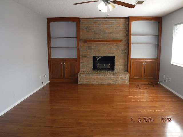 unfurnished living room featuring a brick fireplace, wood finished floors, and baseboards