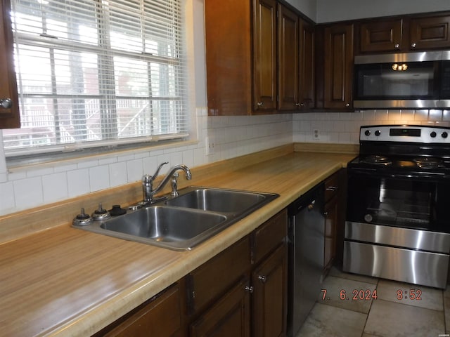 kitchen with tile patterned flooring, appliances with stainless steel finishes, backsplash, and a sink