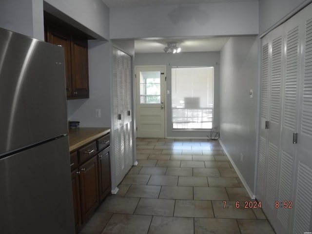 kitchen with light tile patterned floors, baseboards, light countertops, and freestanding refrigerator