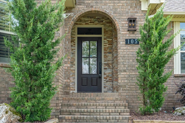 view of exterior entry featuring brick siding