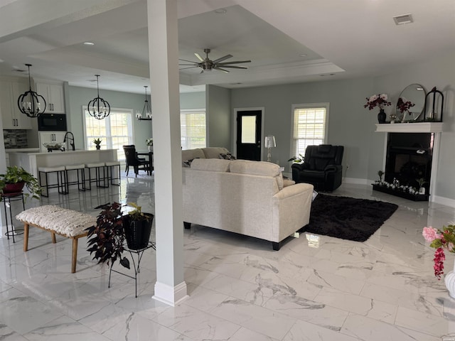 202 Quail Ridge Dr, Hot Springs, AR 71901 - living area featuring a chandelier, light marble finish flooring, a fireplace, a ceiling fan, and a tray ceiling