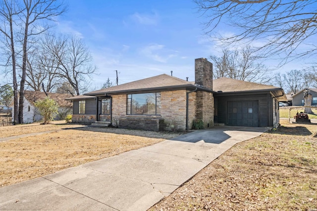 view of front facade with a garage, stone siding, driveway, and a chimney