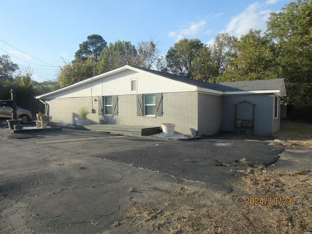 view of home's exterior with uncovered parking and brick siding