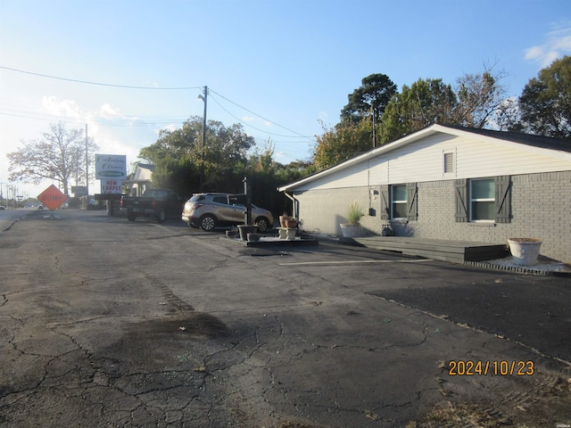 view of side of home with uncovered parking and brick siding