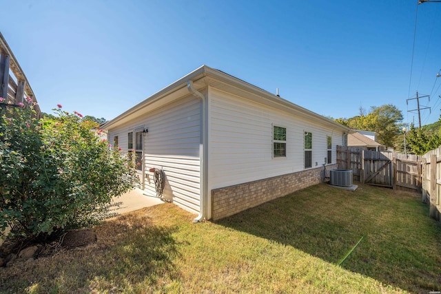 view of property exterior featuring a lawn, a fenced backyard, a gate, and central air condition unit