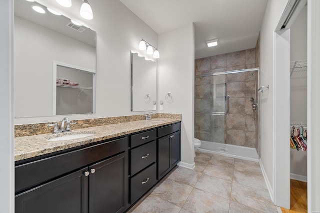 bathroom featuring a shower stall, a spacious closet, and a sink