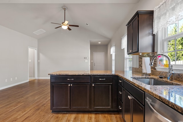 kitchen featuring stainless steel dishwasher, light wood-style floors, a sink, dark brown cabinets, and a peninsula