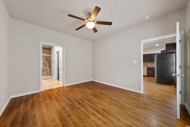 unfurnished bedroom with light wood-type flooring, ceiling fan, baseboards, and freestanding refrigerator