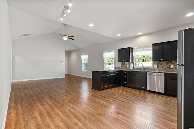 kitchen with visible vents, open floor plan, light stone countertops, stainless steel appliances, and a sink