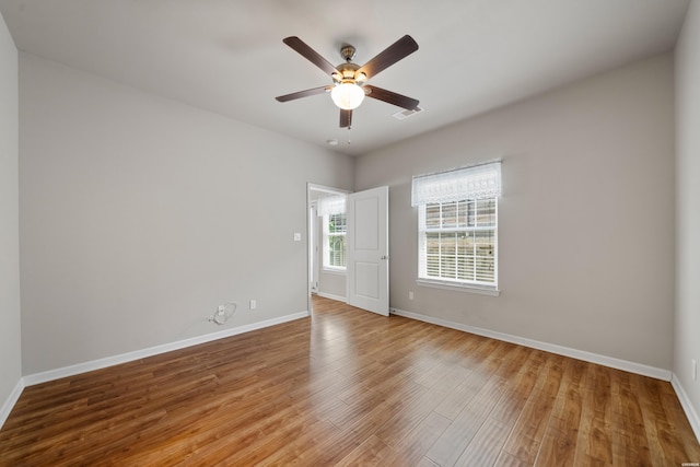 unfurnished room featuring ceiling fan, wood finished floors, visible vents, and baseboards